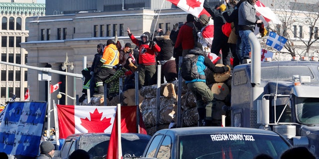 FILE PHOTO: Demonstrators stand on a trailer carrying logs as truck drivers and supporters participate in a convoy to protest mandates for a coronavirus (COVID-19) vaccine for cross-border truck drivers in Ottawa, Ontario, Canada, Jan. 29, 2022. REUTERS/PATRICK DOYLE/FILE Picture