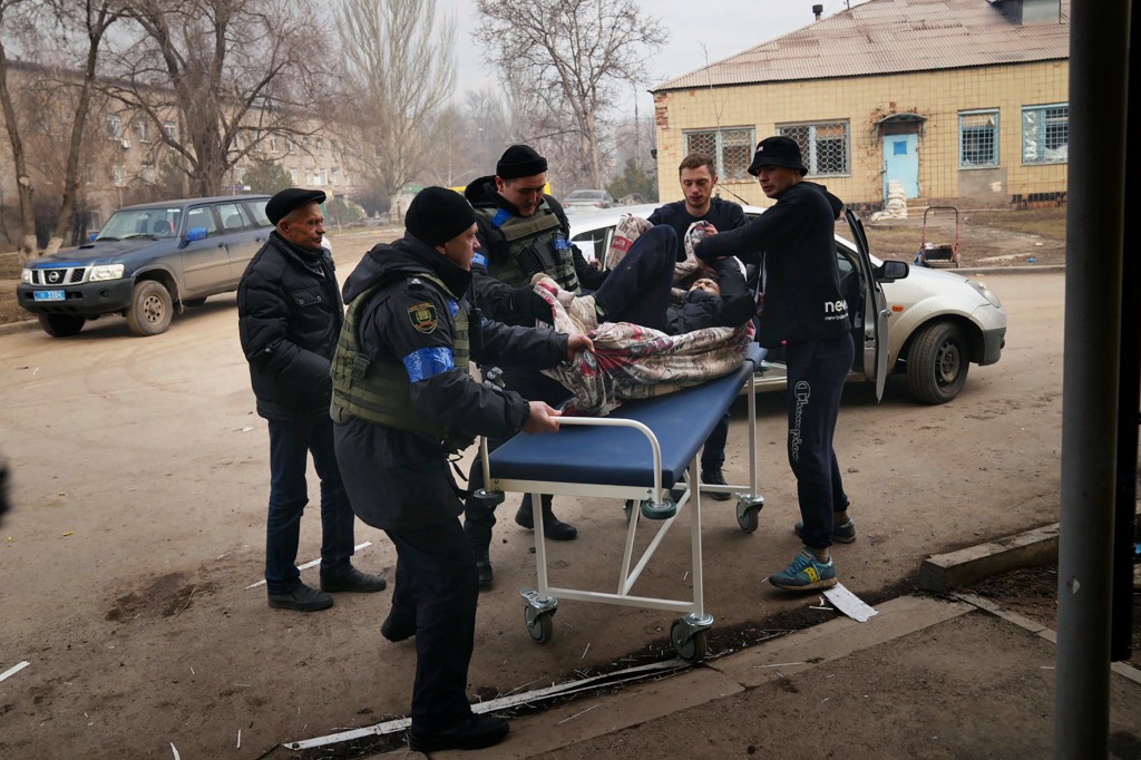 Ukrainian soldiers and volunteers carry a man wounded during a bombing attack.