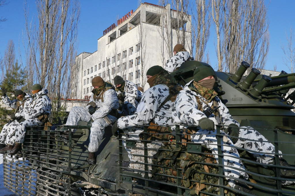 Service personnel ride atop an armored personnel carrier during tactical exercises, conducted by the Ukrainian National Guard, Armed Forces, special operations units and simulating a crisis situation in an urban settlement in the abandoned city of Pripyat near the Chernobyl nuclear power plant, Ukraine February 4, 2022.
