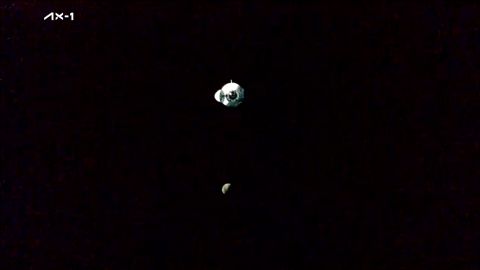 The SpaceX Ax-1 Dragon capsule approaches the International Space Station, the moon in the background.
