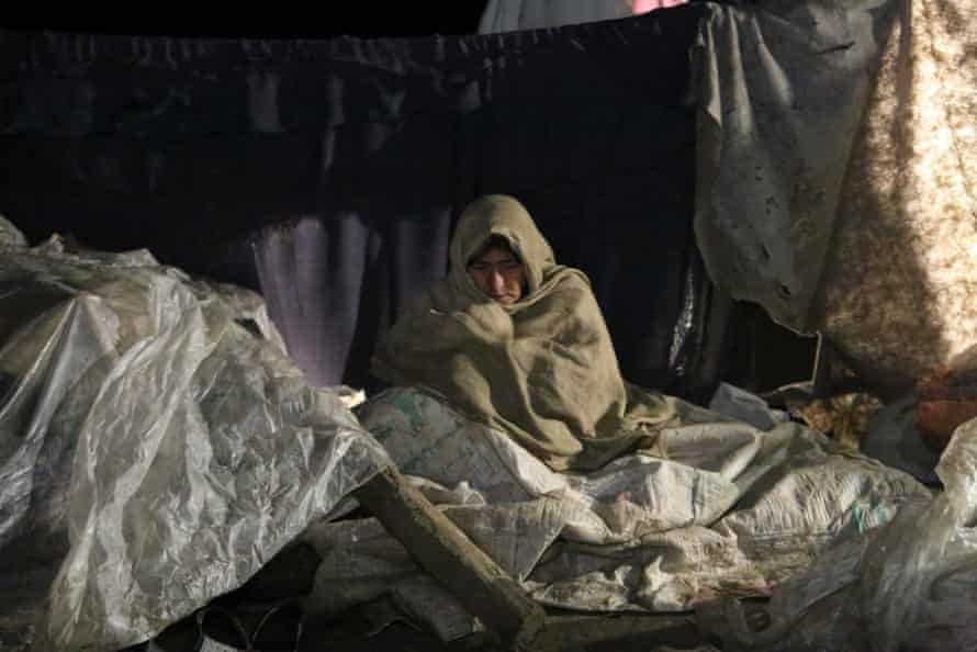 A woman in Paktika state left homeless by the earthquake tries to keep warm.