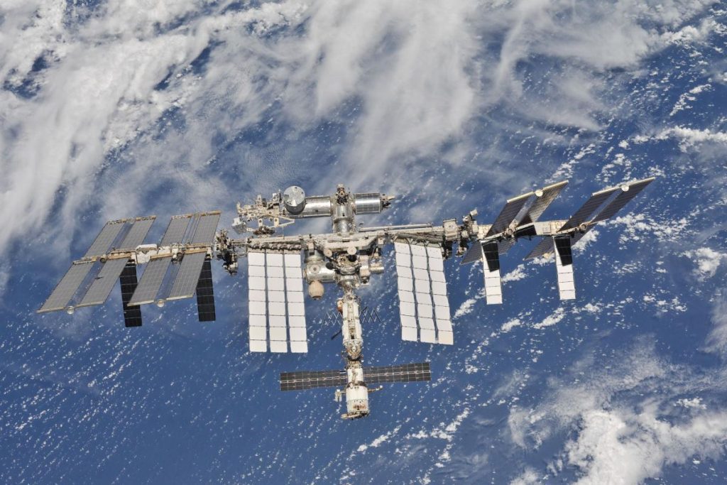The international space station can be seen in the foreground with the blue and white of Earth behind it.