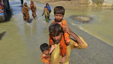 A displaced person carries his daughters from his flood-damaged home in Jafarabad, a suburb of Pakistan's southwestern Balochistan province, on Saturday. 